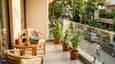 East-facing first-floor balcony morning lifestyle image showing 14x6 ft outdoor space with cane chairs, coffee, plants, and golden morning light over the neighbourhood