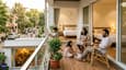 South-facing G+1 home lifestyle — family on the balcony, street view below, afternoon light filling the living room