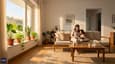 Bright morning living room of east facing single floor home with family, warm sunlight through large east windows, plants on windowsill and minimal modern interiors